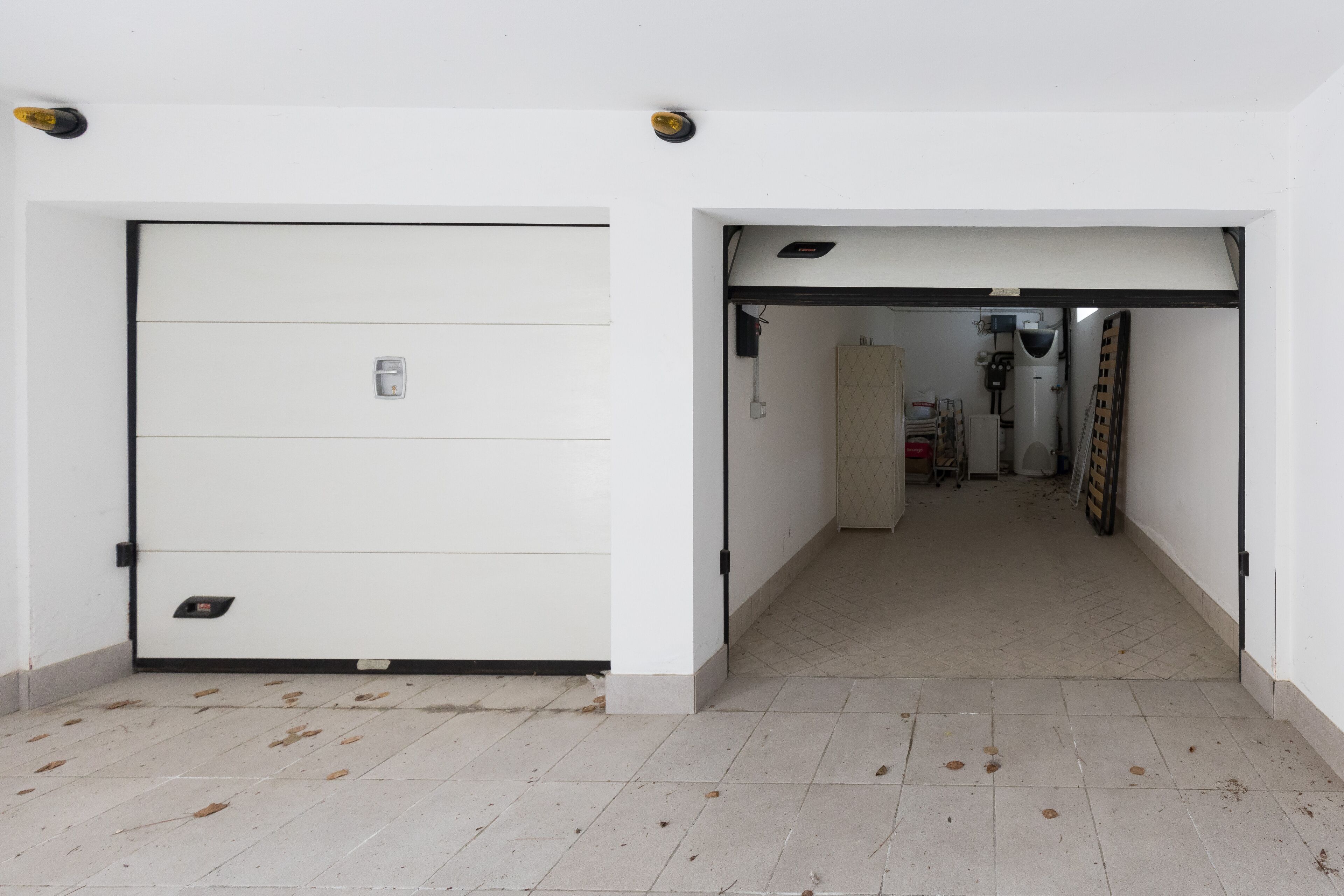 A hallway with a closed white door on the left and an open door on the right leading to a room with a bed and a wardrobe.