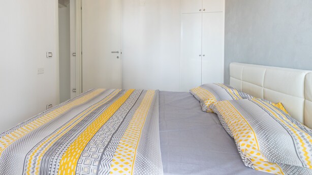 Un dormitorio con cama, almohadas y un armario.