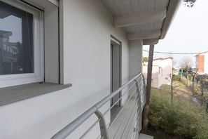 Een balkon met een metalen hekwerk, een raam en een deur.