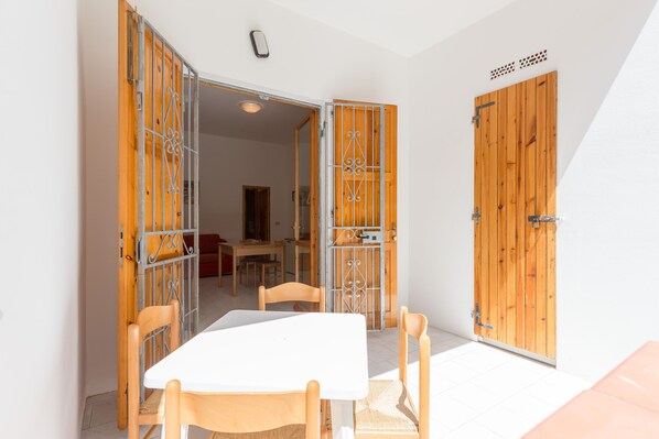 A room with a white table and chairs, wooden doors with metal gates, and a visible ceiling light.