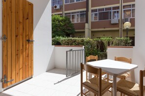 A small patio area with a wooden door, a white table, and wicker chairs.
