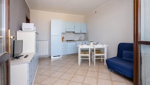 A compact living space with a kitchenette, a dining area, and a sofa. - Residence Smith - Piano Terra 2A (Comacchio)