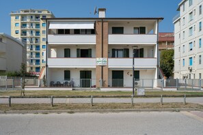 A multi-story building with balconies, a signboard, and a gated entrance.