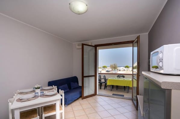 A compact living space with a dining area, a sofa, and a balcony with a table and chairs. - Residence Smith 2 Piano Laterale E 3C (Comacchio)