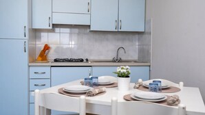A modern kitchen with light blue cabinets, a white dining table set for four, and a small potted plant on the table. - Residence Smith 2 Piano Laterale E 3C (Comacchio)