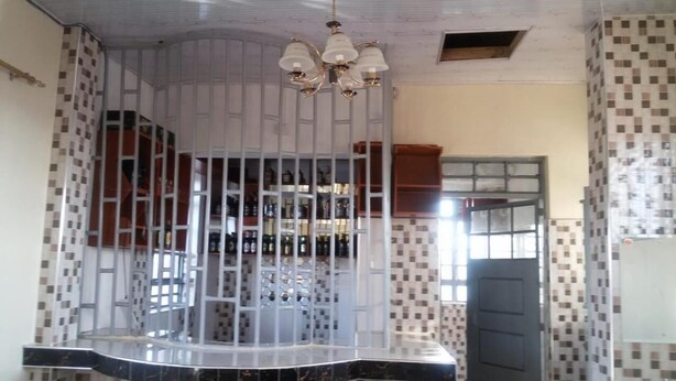 Une pièce avec un mur recouvert de carreaux, un lustre et une porte dotée d’une fenêtre.