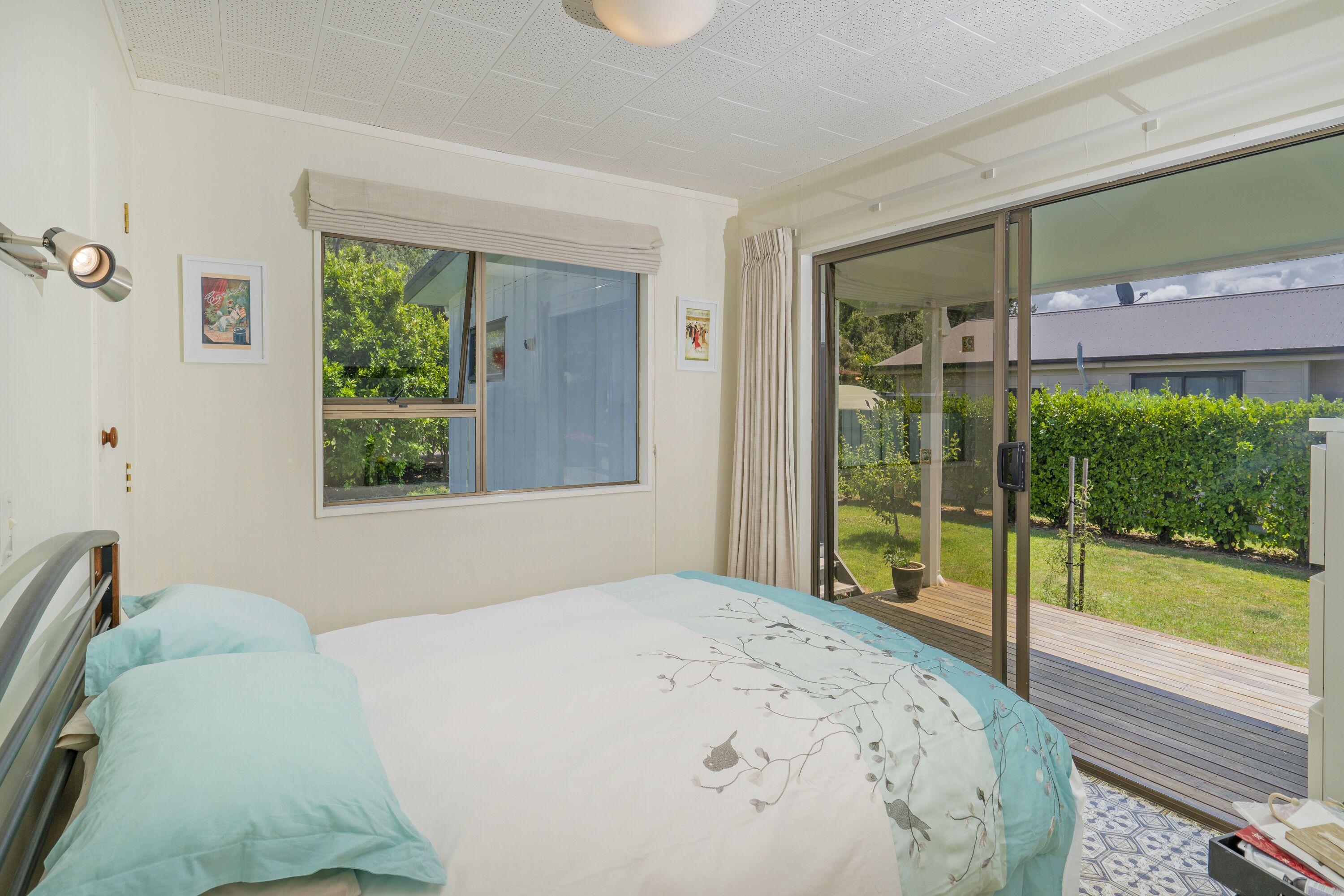 A bedroom with a bed, a window, and a sliding glass door leading to a balcony.