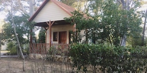 A small, single-story house with a porch, surrounded by trees and vegetation. - Camping Playa Las Dunas (El Puerto de Santa Maria)