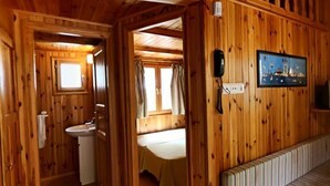 Ein Holzblockbau-Innenraum mit Bad, einem Bett, einem Telefon und einem Fernseher.