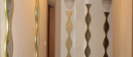 Un pasillo con espejos decorativos en la pared y suelo de baldosas.