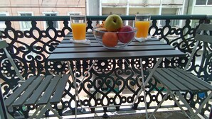Un balcón con una mesa dispuesta con frutas y vasos de jugo de naranja.