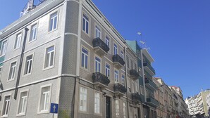 Un edificio de varios pisos con fachada ornamentada, balcones y automóviles estacionados a lo largo de la calle.