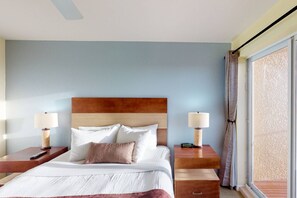 Habitación de hotel con cama, dos mesitas de noche, dos lámparas, cabecero y una ventana con cortinas.