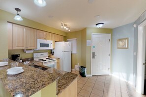 A kitchen with granite countertops, a stove, a microwave, and a refrigerator.