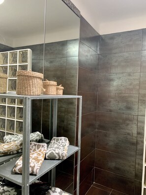 Ein Zimmer mit einem Metallregal, das gemusterte Handtücher und gewebte Körbe beherbergt.