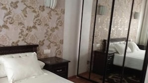 Een hotelkamer met een groot bed, een garderobe met spiegel en een nachtkastje.