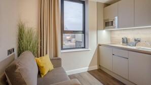 Een moderne keuken met een ingebouwde magnetron, een raam met gordijnen en een houten vloer.
