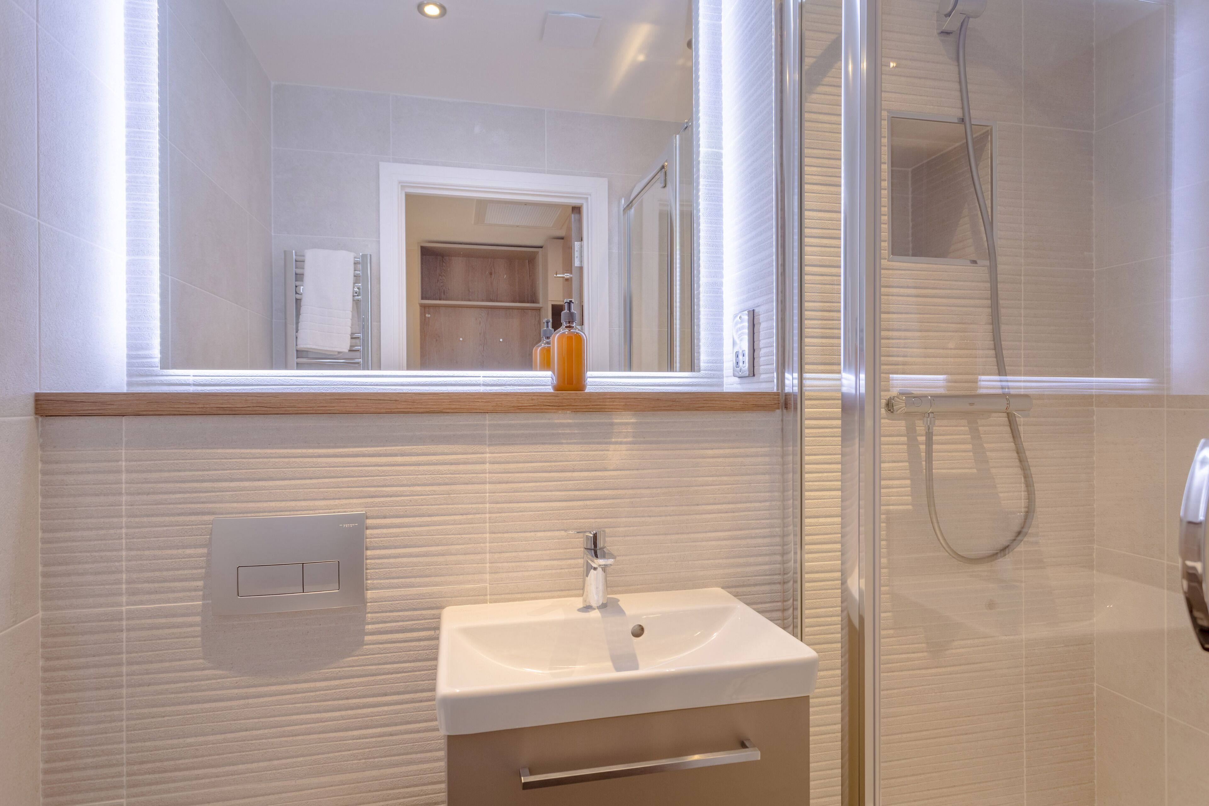 A modern bathroom with a white sink, mirror, and shower.