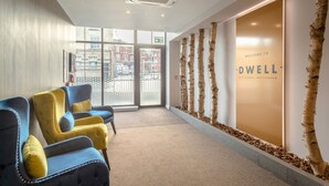 Een receptiegedeelte met een modern ontwerp, met een groot bord dat gasten verwelkomt bij DWELL in Nottingham.