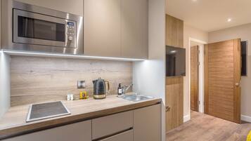 A modern kitchen with a built-in microwave, kettle, and sink.