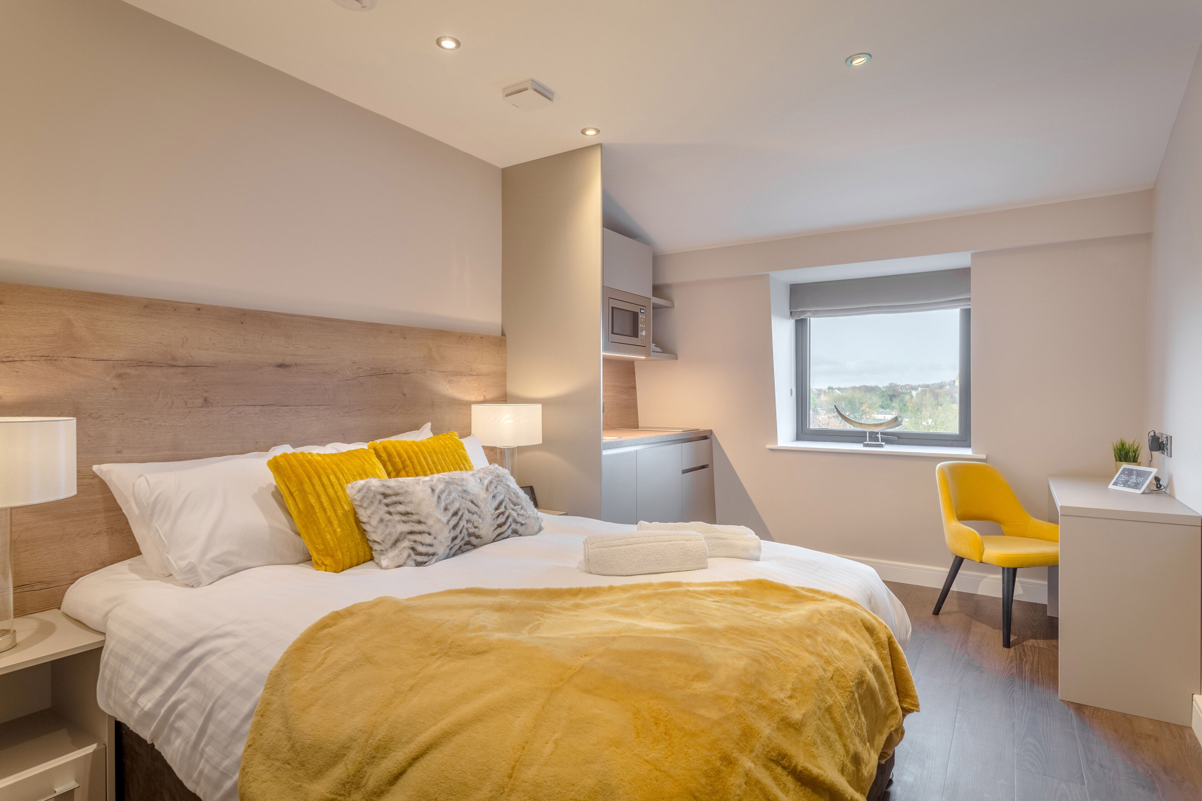 A modern hotel room with a large bed, a desk, and a view of the city.