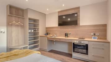 A modern kitchen with a built-in oven, a sink, and a flat-screen TV mounted above the countertop.