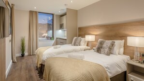 Een hotelkamer met twee bedden, een bureau, een lamp en uitzicht op de skyline.