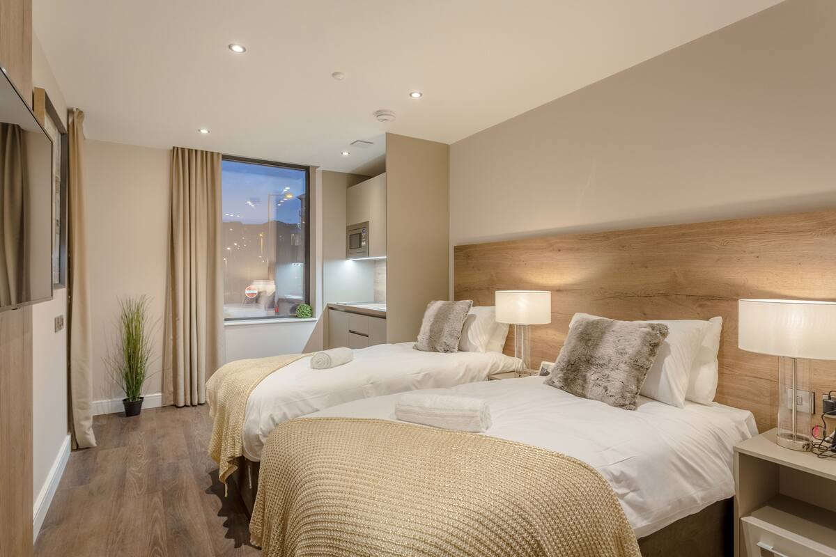 Une chambre d’hôtel avec deux lits, un bureau, une lampe et une vue sur le paysage urbain.