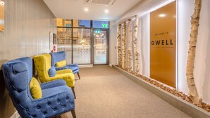 Een receptiegedeelte met een modern design, met een receptiebalie, een zithoek met blauwe en gele stoelen, en een groot welkomstbord.