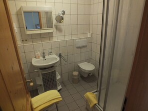 A small, tiled bathroom with a sink, mirror, toilet, and shower. - Appartements & Reitschule Fuchsenhof (Neunburg vorm Wald)