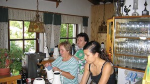Eine Küche mit einer Kaffeemaschine, einem Wasserkocher und einem Teekessel auf der Arbeitsplatte. Darüber befindet sich ein Kühlschrank mit Gläsern.