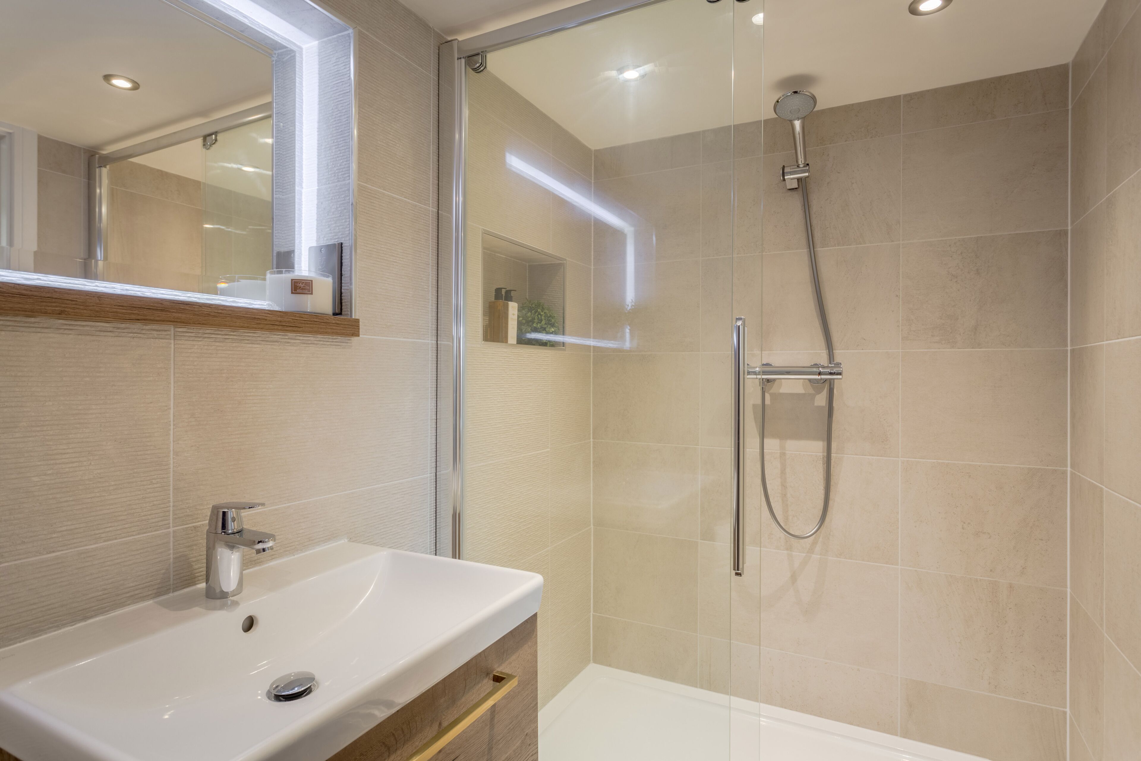 Une salle de bain moderne avec une douche en verre, un lavabo blanc et un miroir au-dessus du lavabo.