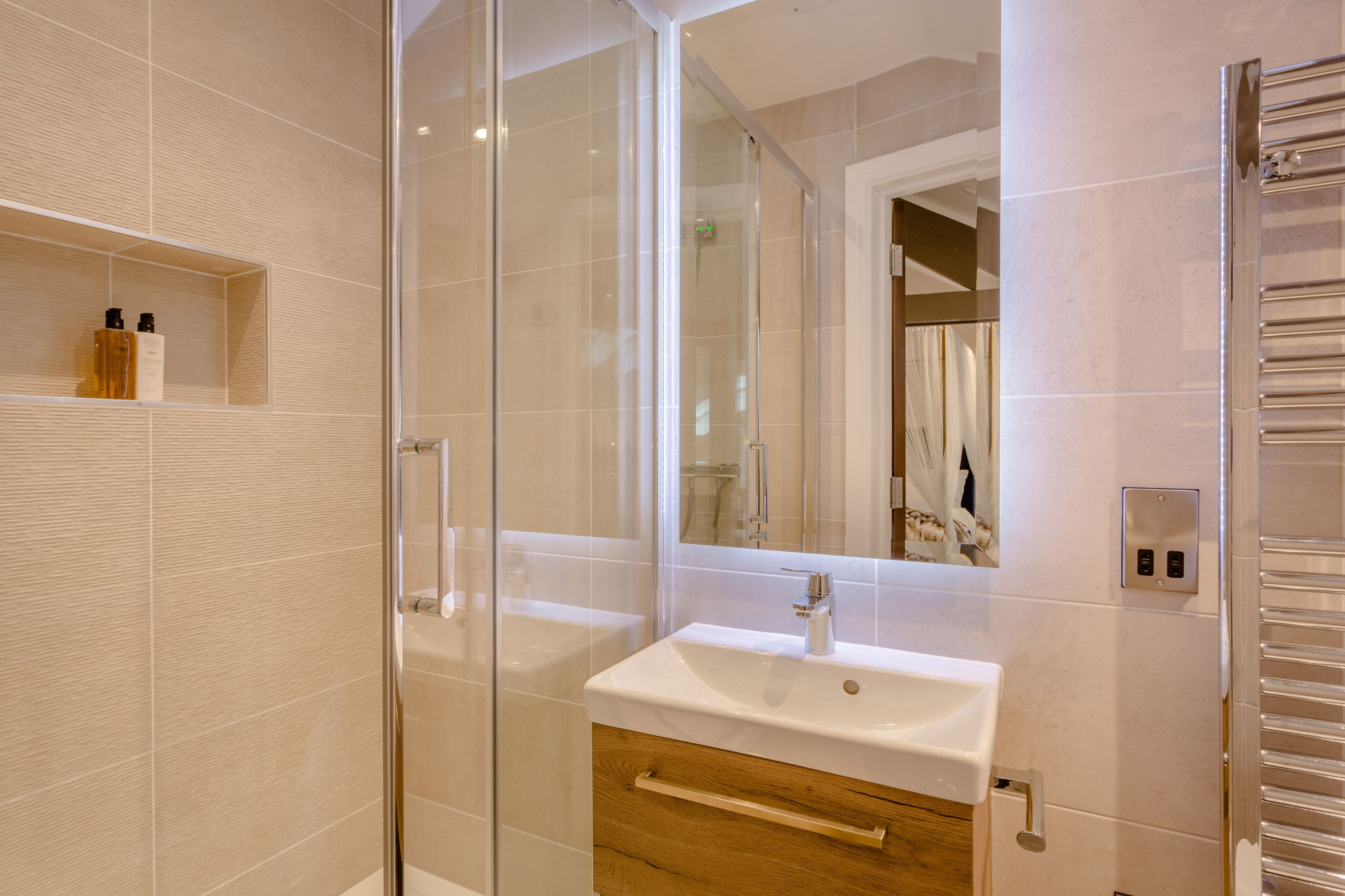 Ein modernes Badezimmer mit einer Duschkabine aus Glas, einem weißen Waschbecken und einem Holzbadezimmer-Möbel.
