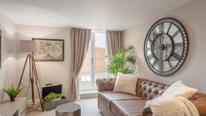 Una sala de estar moderna con un sofá de cuero, un reloj de pared grande, una obra de arte con un globo terráqueo y una planta en maceta.