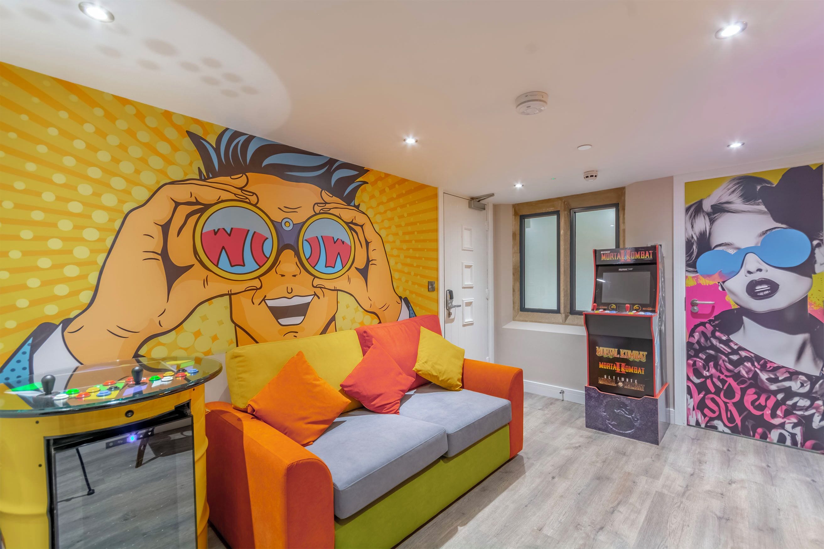 Una habitación con un mural colorido, un sofá con cojines y una mesita con un juguete.