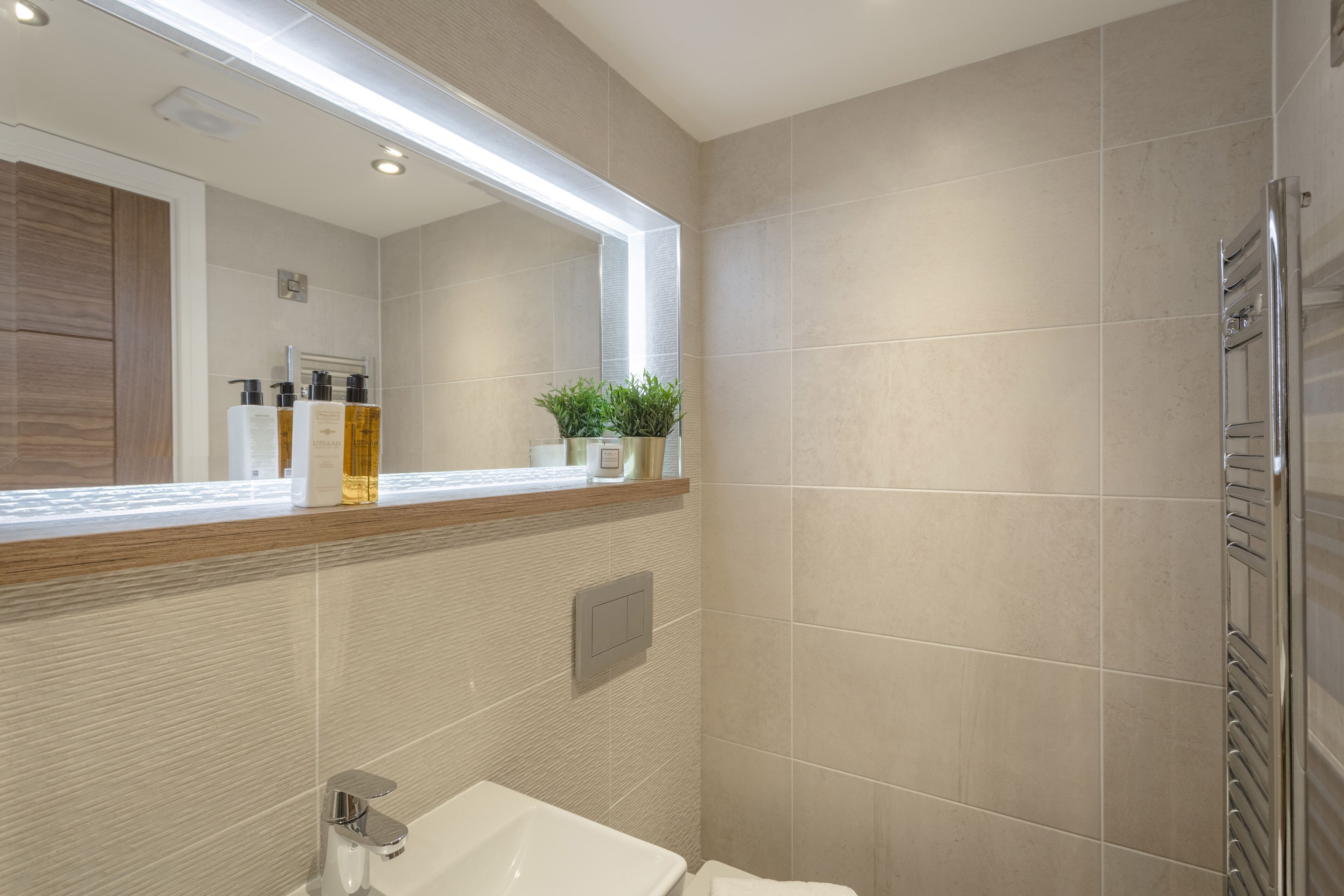 A modern bathroom with a large mirror, a sink, and a shower area.