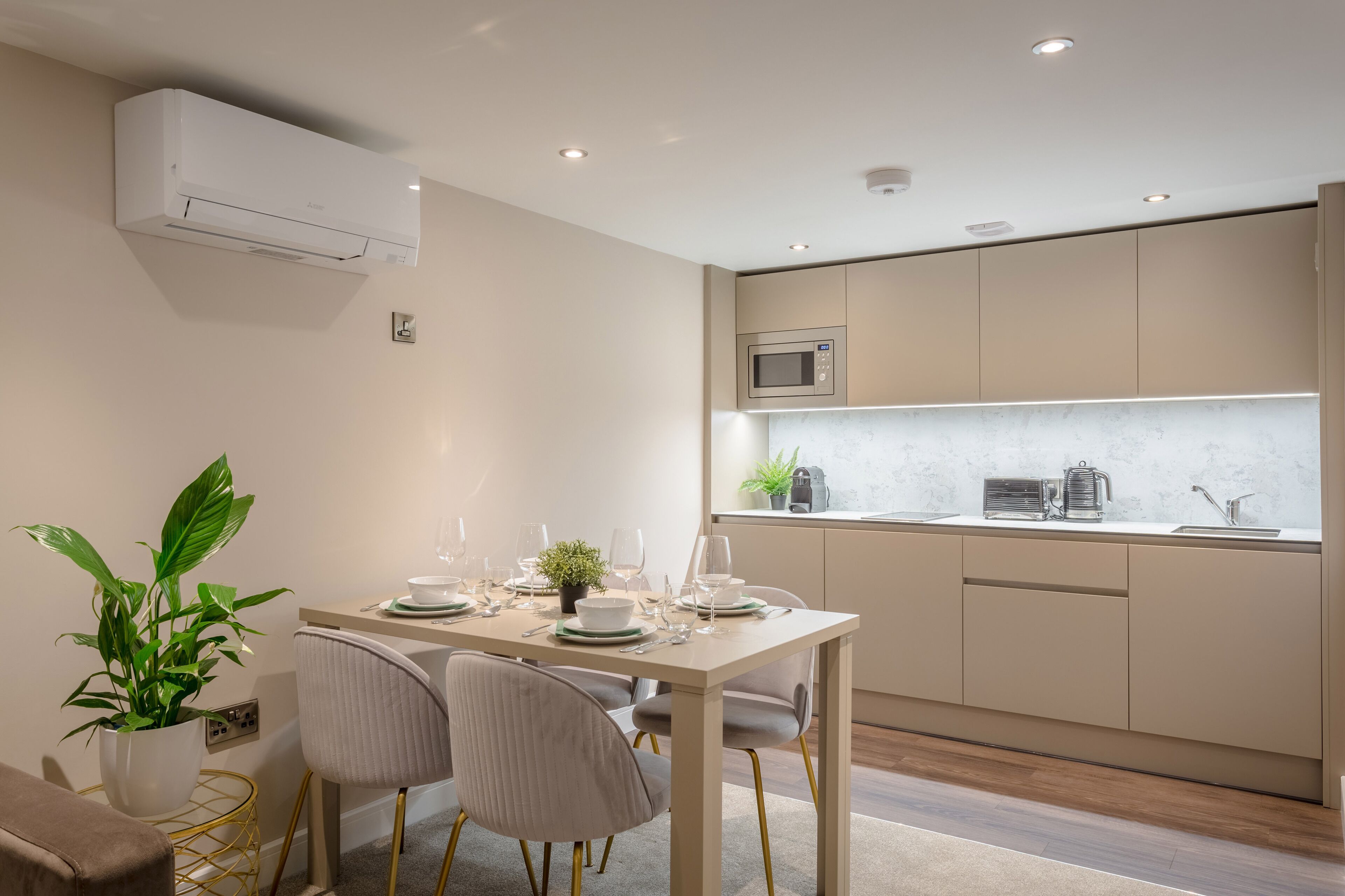 A modern kitchen with a dining area, featuring a built-in microwave, a sink, and a potted plant.