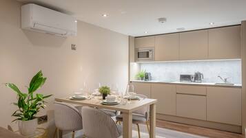 A modern kitchen with a dining area, featuring a built-in microwave, a sink, and a potted plant.