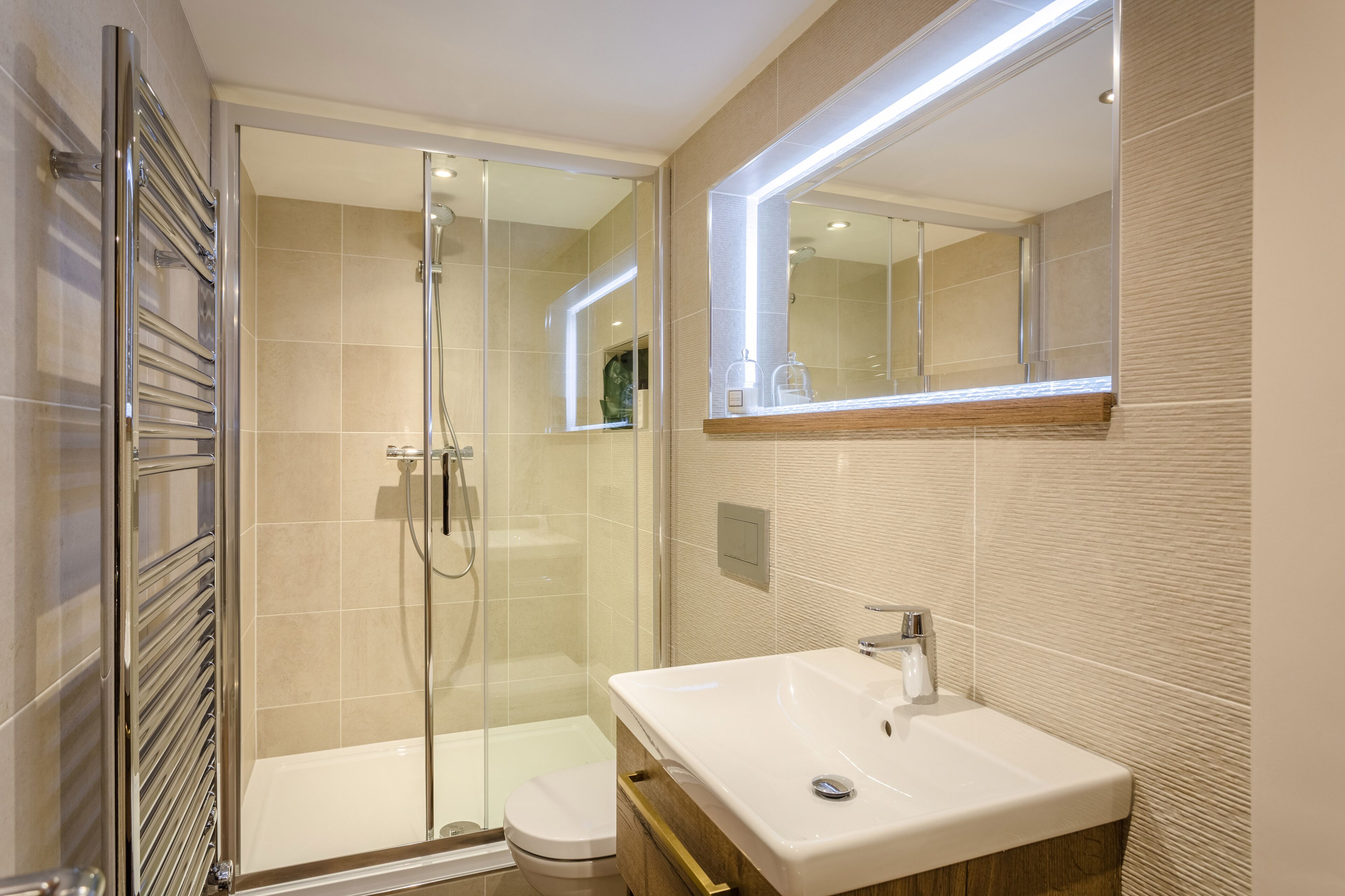 A modern bathroom with a glass-enclosed shower, a white sink, and a large mirror.