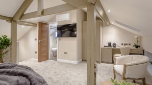 Un dormitorio moderno con techo inclinado, una cama grande, un escritorio y una silla.