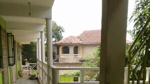 A corridor with tiled flooring leading to a balcony with a view of a house. - Greenview Guest House (Kisumu)