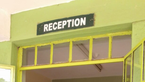 A reception area with a painted mural of a sunset landscape and a sign above the door that reads "RECEPTION". - Greenview Guest House (Kisumu)
