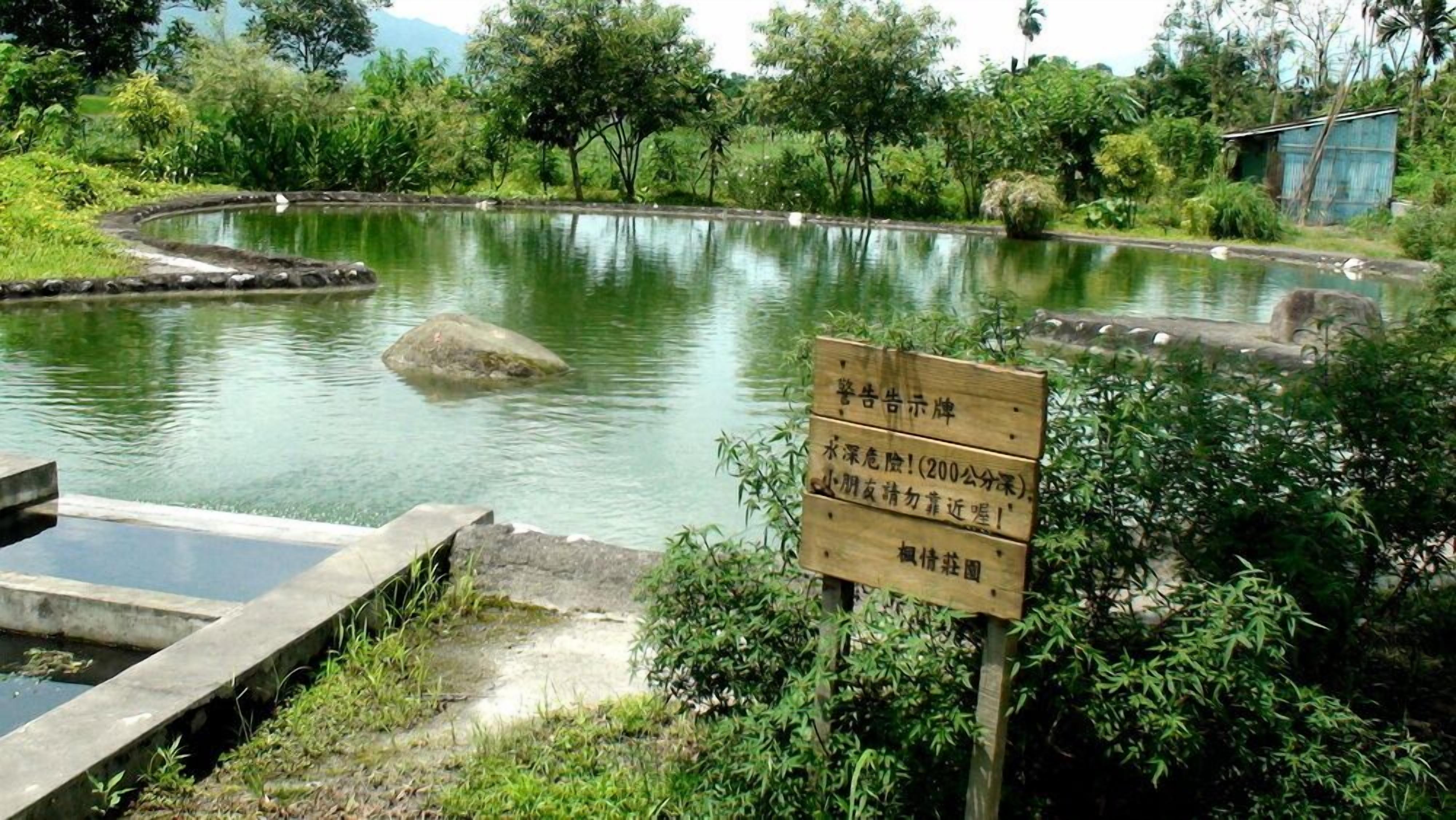 A tranquil pond with a wooden signboard in the foreground.