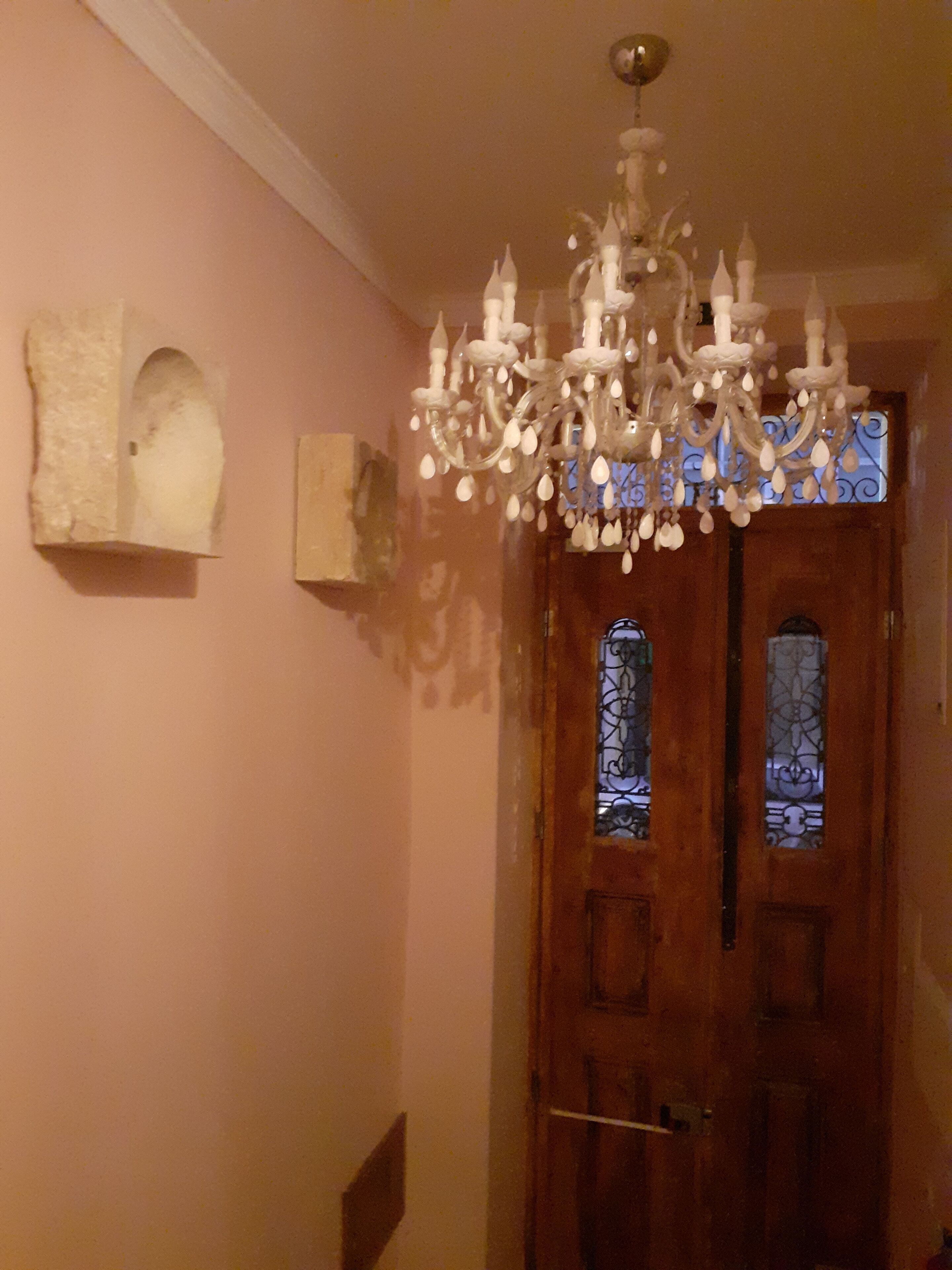 Una habitación con puerta de madera, candelabro y una escultura en la pared.