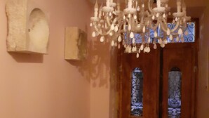 Une pièce dotée d’une porte en bois, d’un lustre et d’une sculpture fixée au mur.