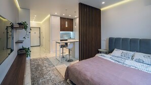 A modern bedroom with a bed, a desk, and a kitchenette. - EcoLoft Studios (Kyiv)