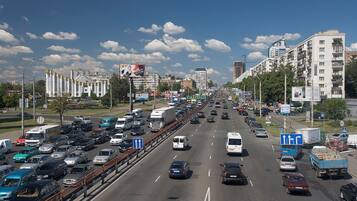 A multi-lane highway with moderate traffic, surrounded by urban buildings and billboards.