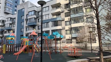 A playground with swings and slides, surrounded by apartment buildings.