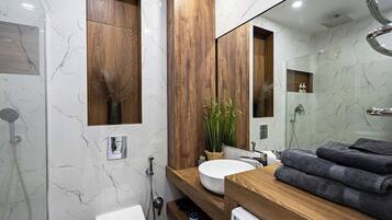 A modern bathroom with a wooden vanity, a large mirror, a white sink, and a shower area.
