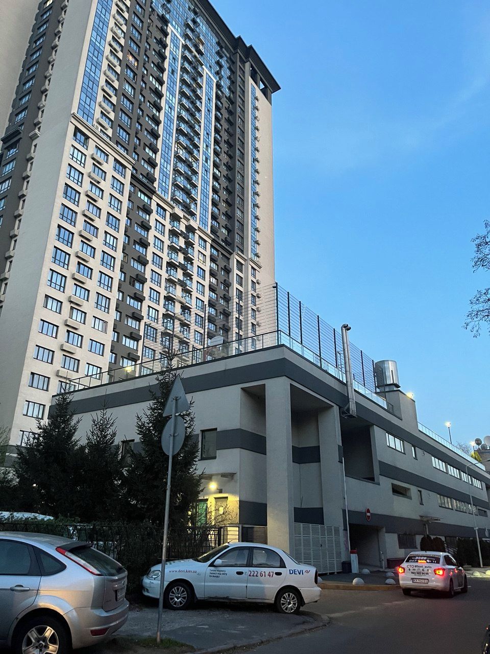 Un immeuble à plusieurs étages, doté d’un design moderne, avec une entrée imposante, une façade en verre et un escalier en métal.